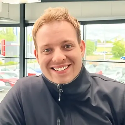 Nicolás Leiser Sánchez Eine lächelnde Person mit kurzen hellen Haaren in schwarzer Jacke, fotografiert in einem hellen Raum mit Fenstern.