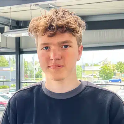 Portrait von Henrik Scheele vor einem großen Fenster in einem hellen Autohaus.